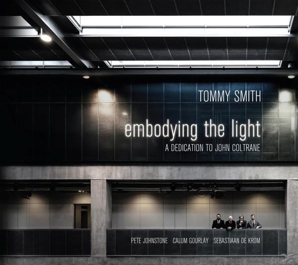 Albumcover. Vier Männer in Anzügen stehen unter einem Schild mit der Aufschrift „embodying the light“.