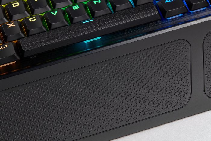 Nahaufnahme einer schwarzen Tastatur mit farbenfroher Beleuchtung. Die Handballenauflage hat ein strukturiertes Design.