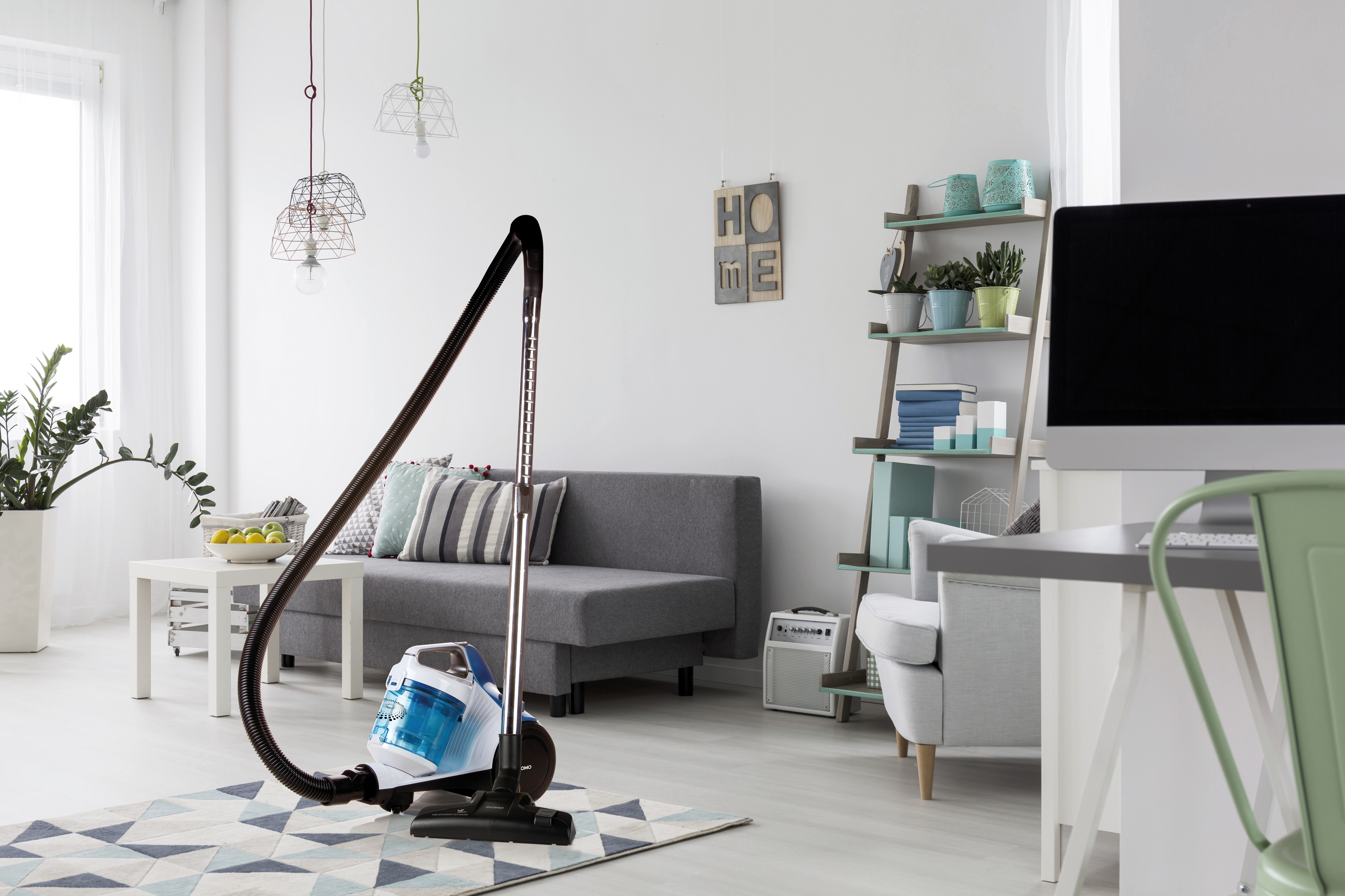 Woonkamer met stofzuiger, bank en bureau.