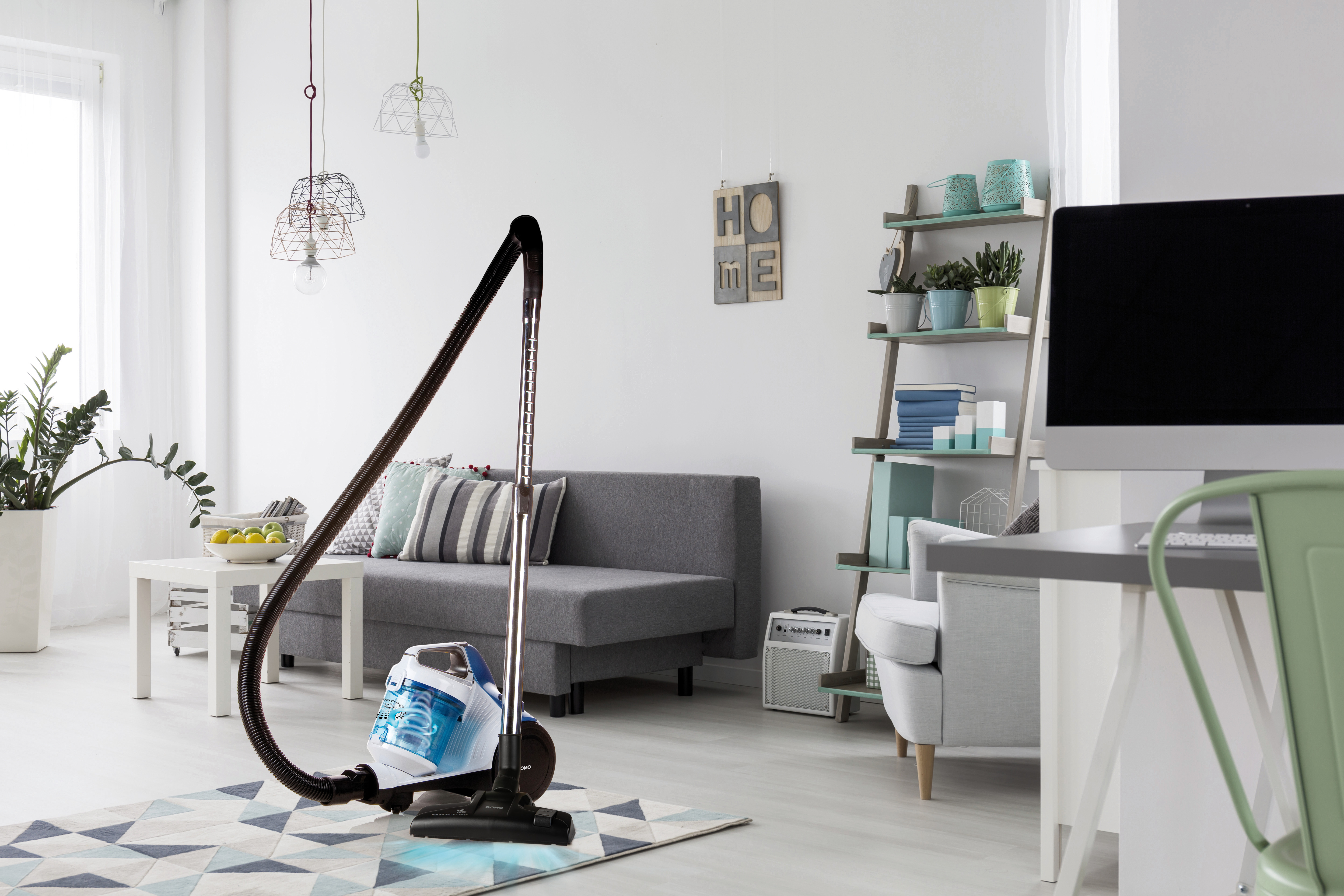 Salon avec un aspirateur en cours d'utilisation, montrant les meubles et la décoration.