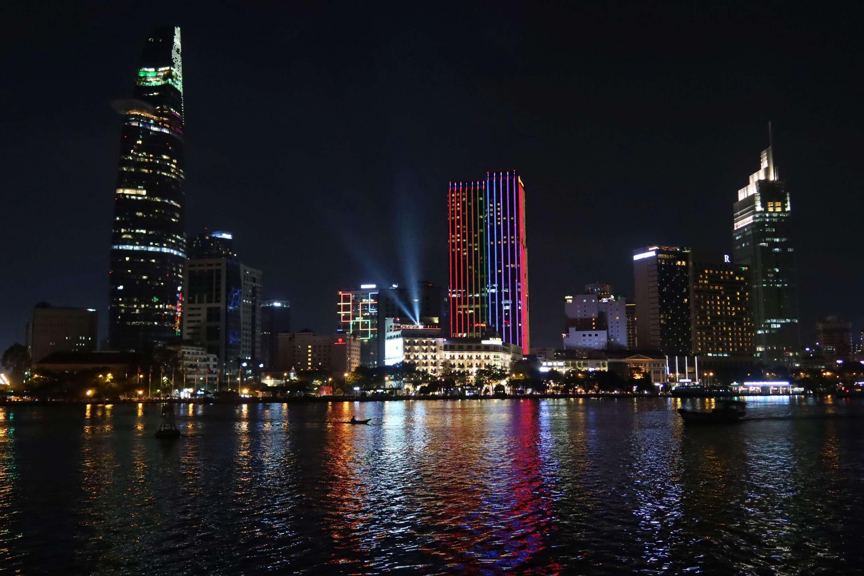 Nachtlandschaft mit beleuchteten Gebäuden. Lichter spiegeln sich im Wasser.