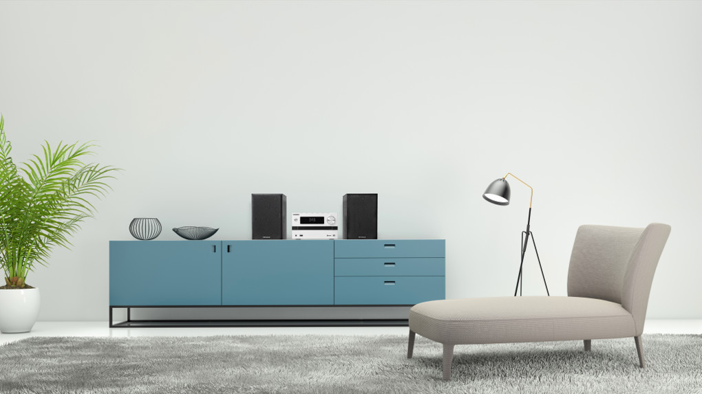 Interieur met een blauwe kast, luidsprekers en een bank. Plant en lamp.