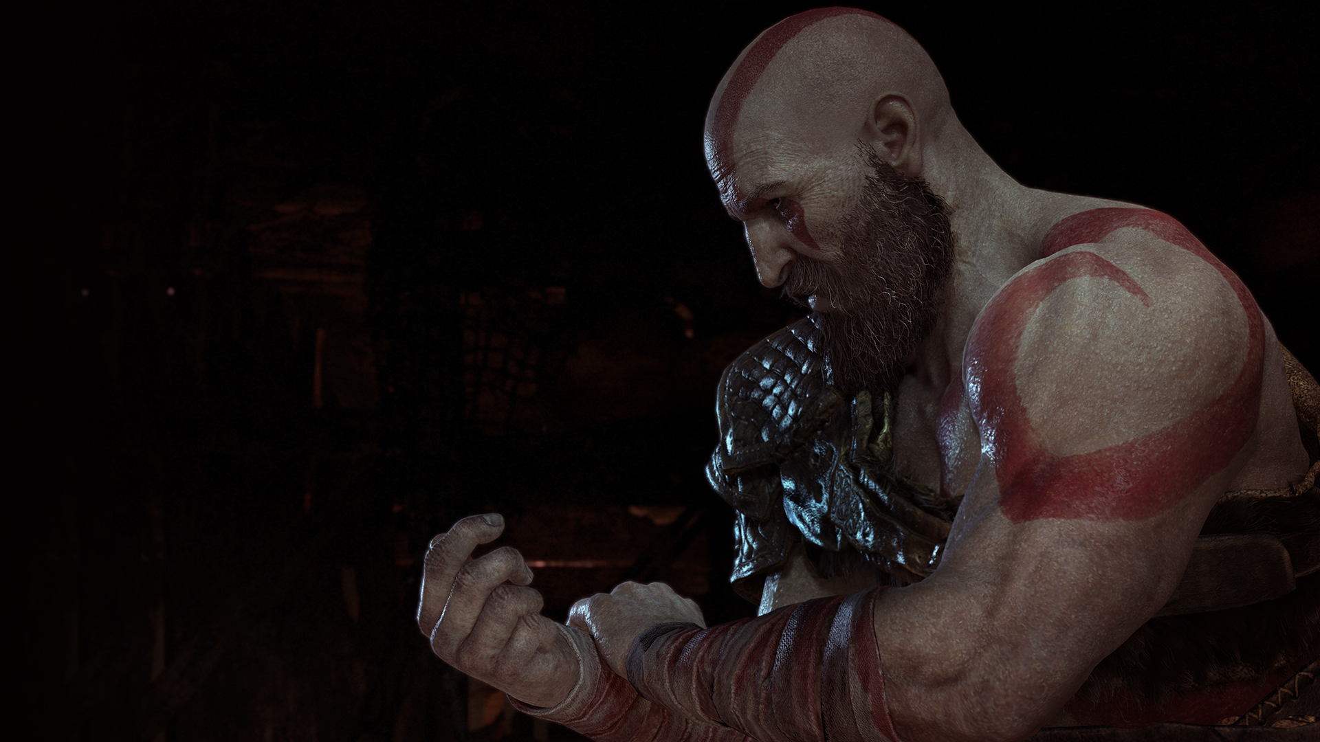 Un homme chauve musclé avec des tatouages rouges, dans une scène sombre, regardant vers le bas.