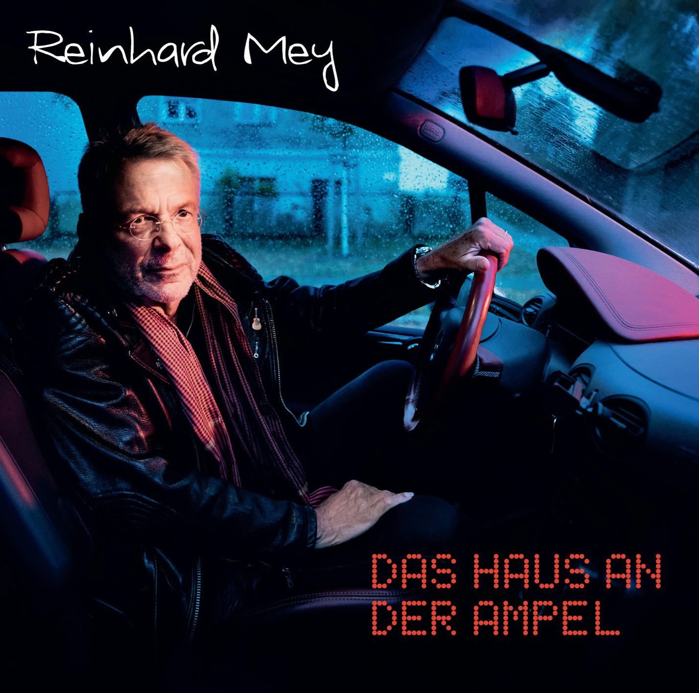 Albumcover mit Reinhard Mey im Auto, mit Text 'DAS HAUS AN DER AMPEL'.