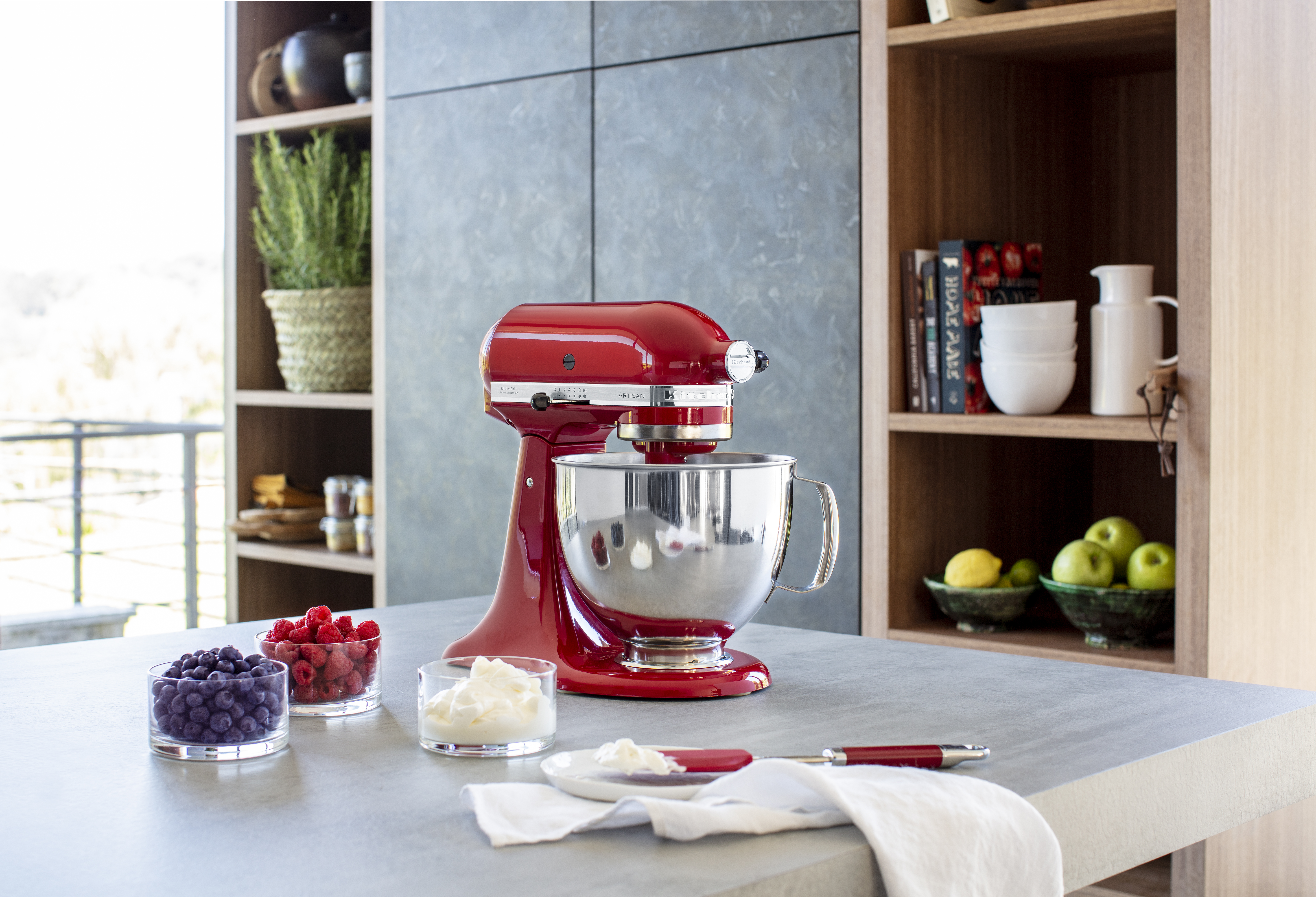 Ein roter Küchenmixer auf einer Theke mit Schüsseln mit Zutaten und anderen Küchenartikeln.