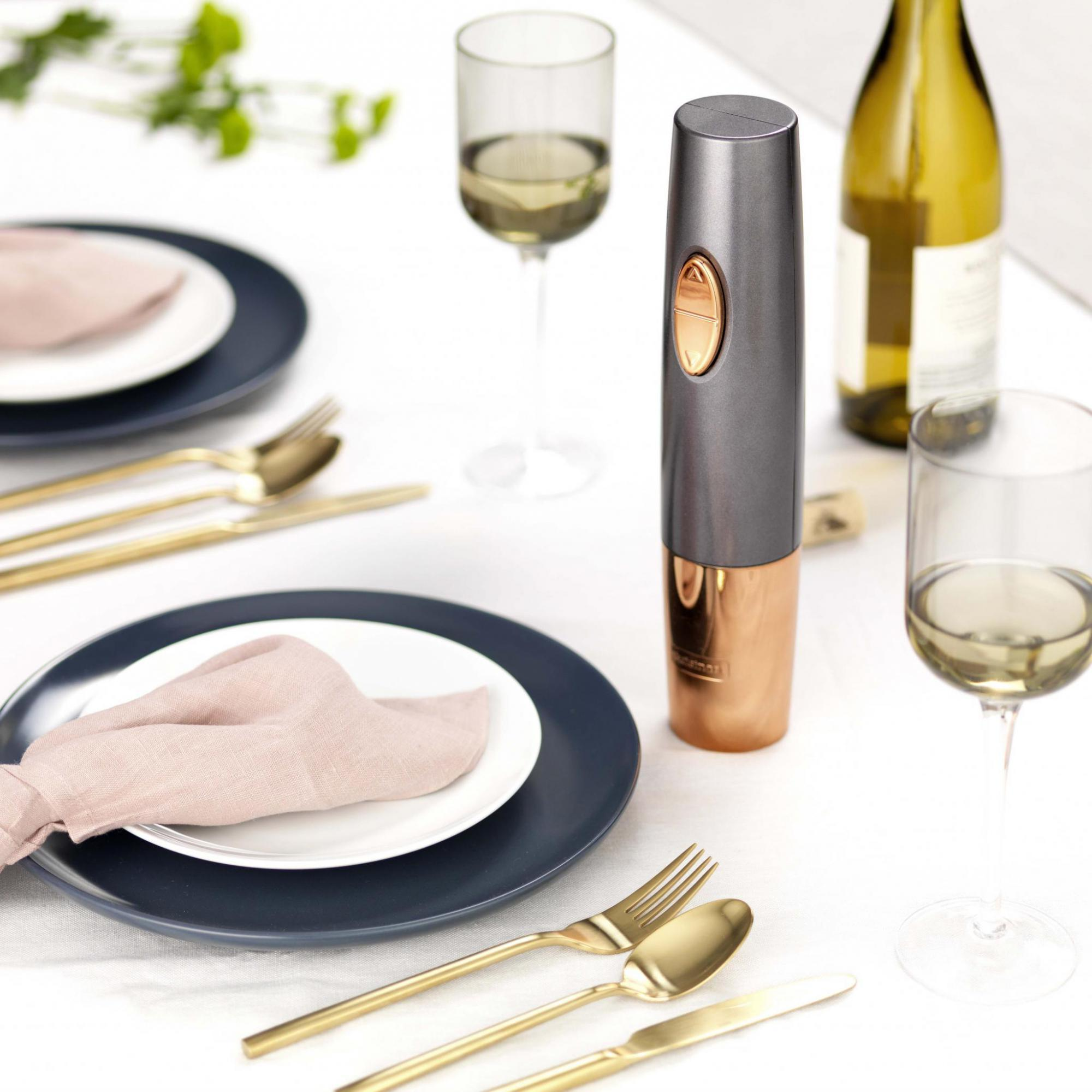 Eine Tischdekoration mit Weingläsern, Tellern und einem Weinöffner.
