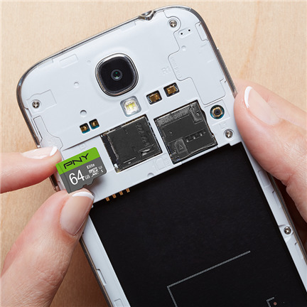 Person legt eine 64GB MicroSD-Karte in einen offenen Smartphone-Schlitz ein.