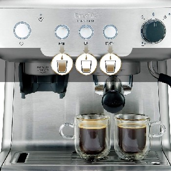 Una máquina de espresso plateada con dos tazas. Dos tazas de espresso con café al frente.