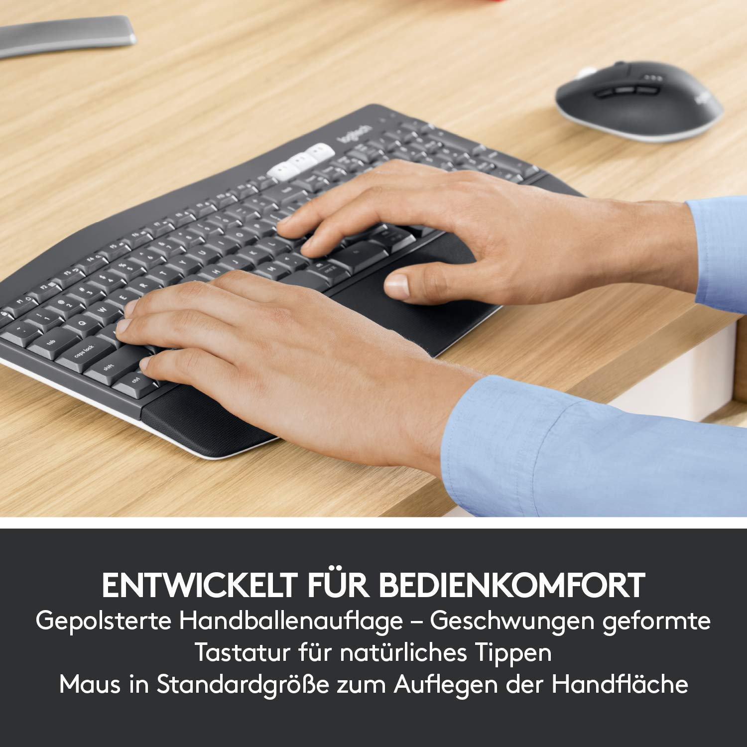Hände auf Tastatur, Maus auf Holzschreibtisch.