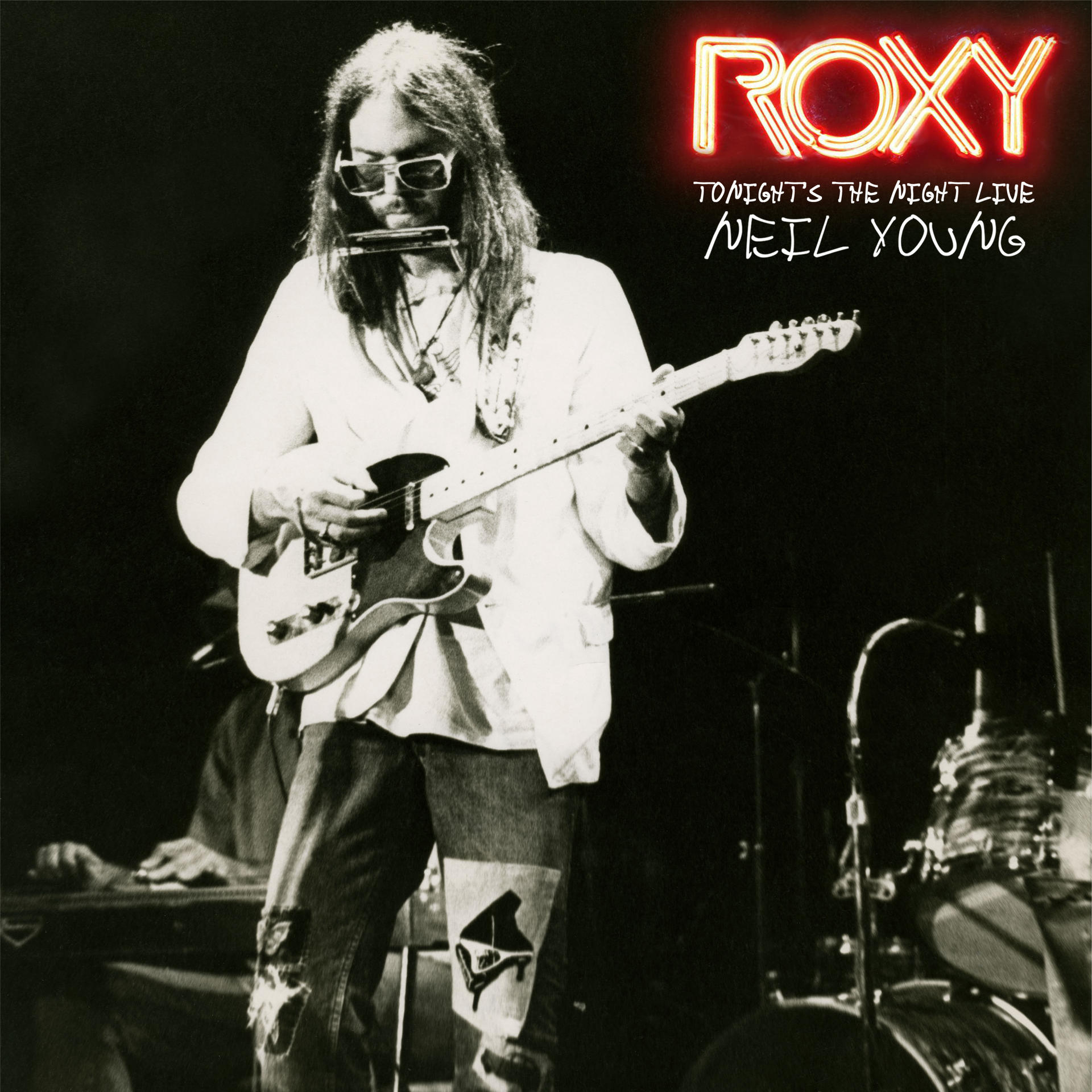 Fekete-fehér kép Neil Young gitározik szájharmonikával és szöveggel.