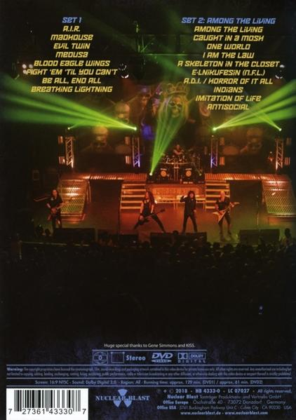 Een live concertpodium met een band die speelt. Setlists zijn zichtbaar. Felle podiumlichten verlichten de muzikanten en het publiek.