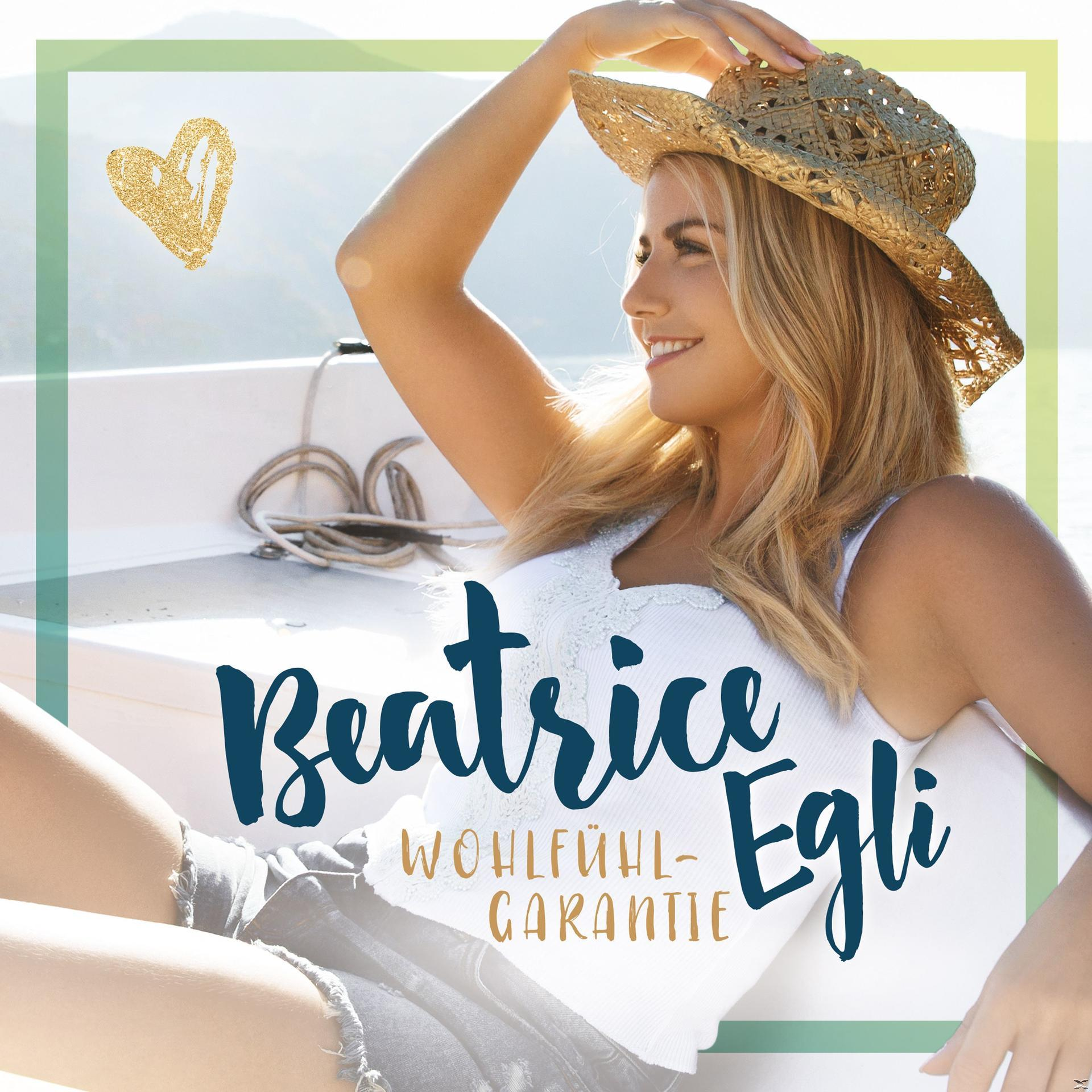 Frau mit Hut lächelt. Text: 'Beatrice Egli' und 'Wohlfühl-Garantie'.