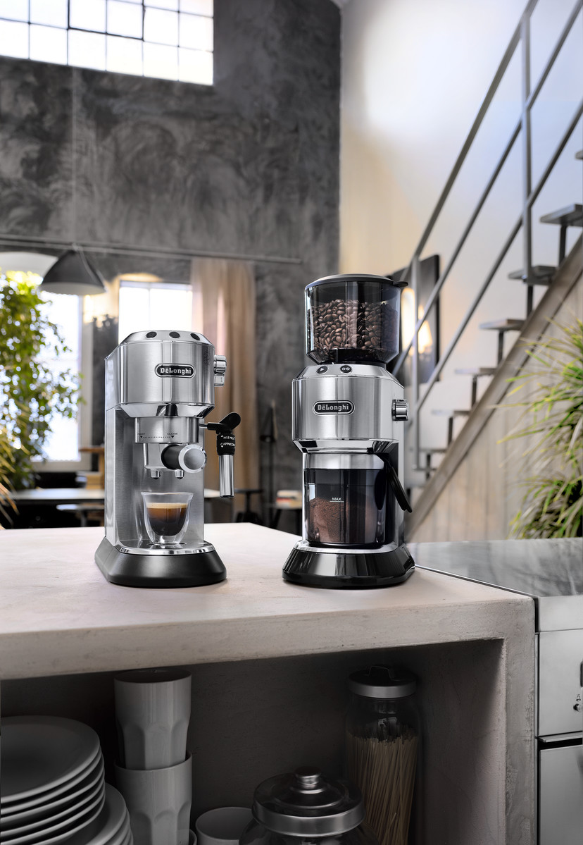 Zwei silberne Espressomaschinen auf einer Theke. Eine mit Mahlwerk.