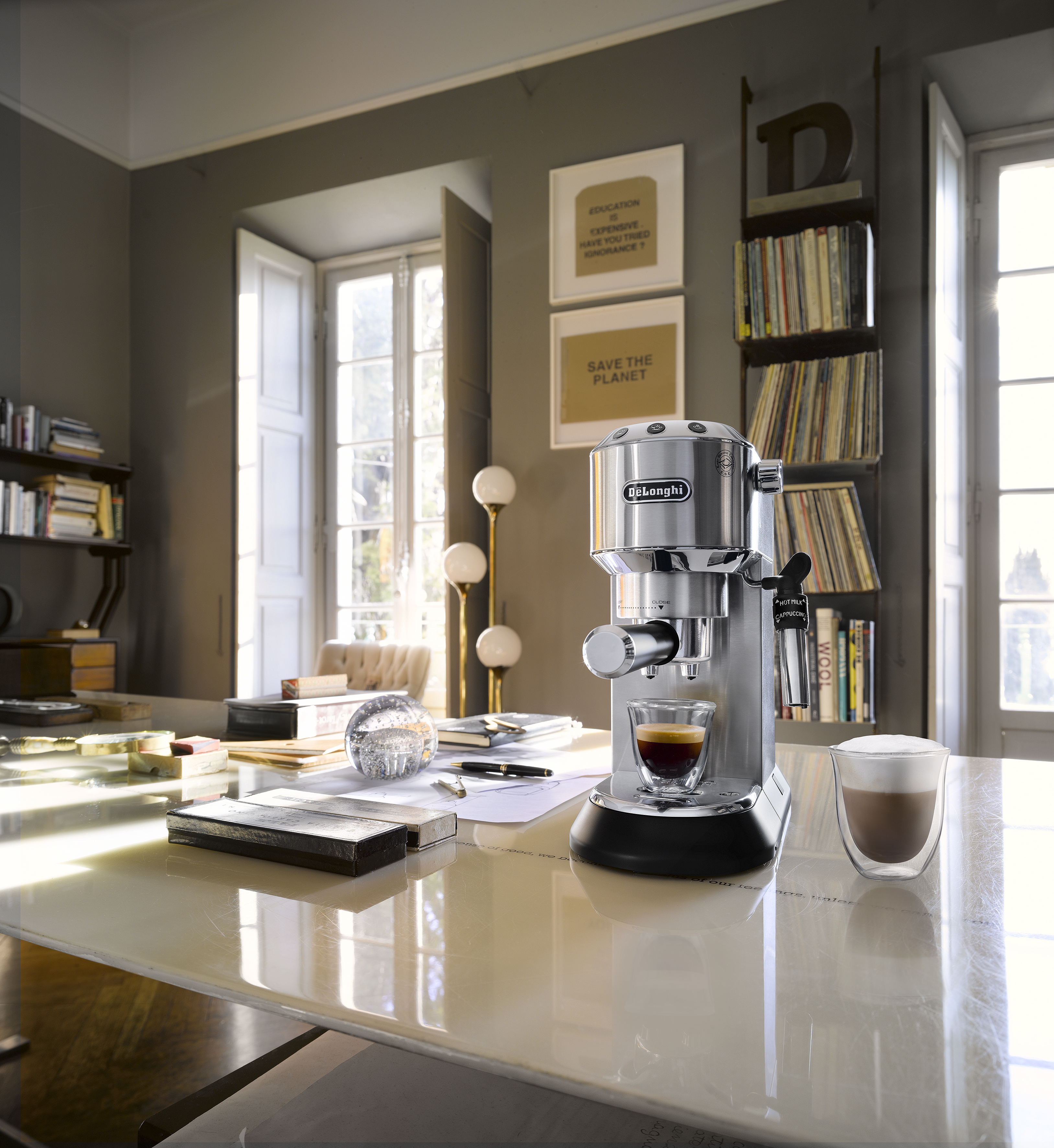 Eine Espressomaschine auf einem Tisch, mit einem Glas Kaffee und Dekor im Hintergrund.