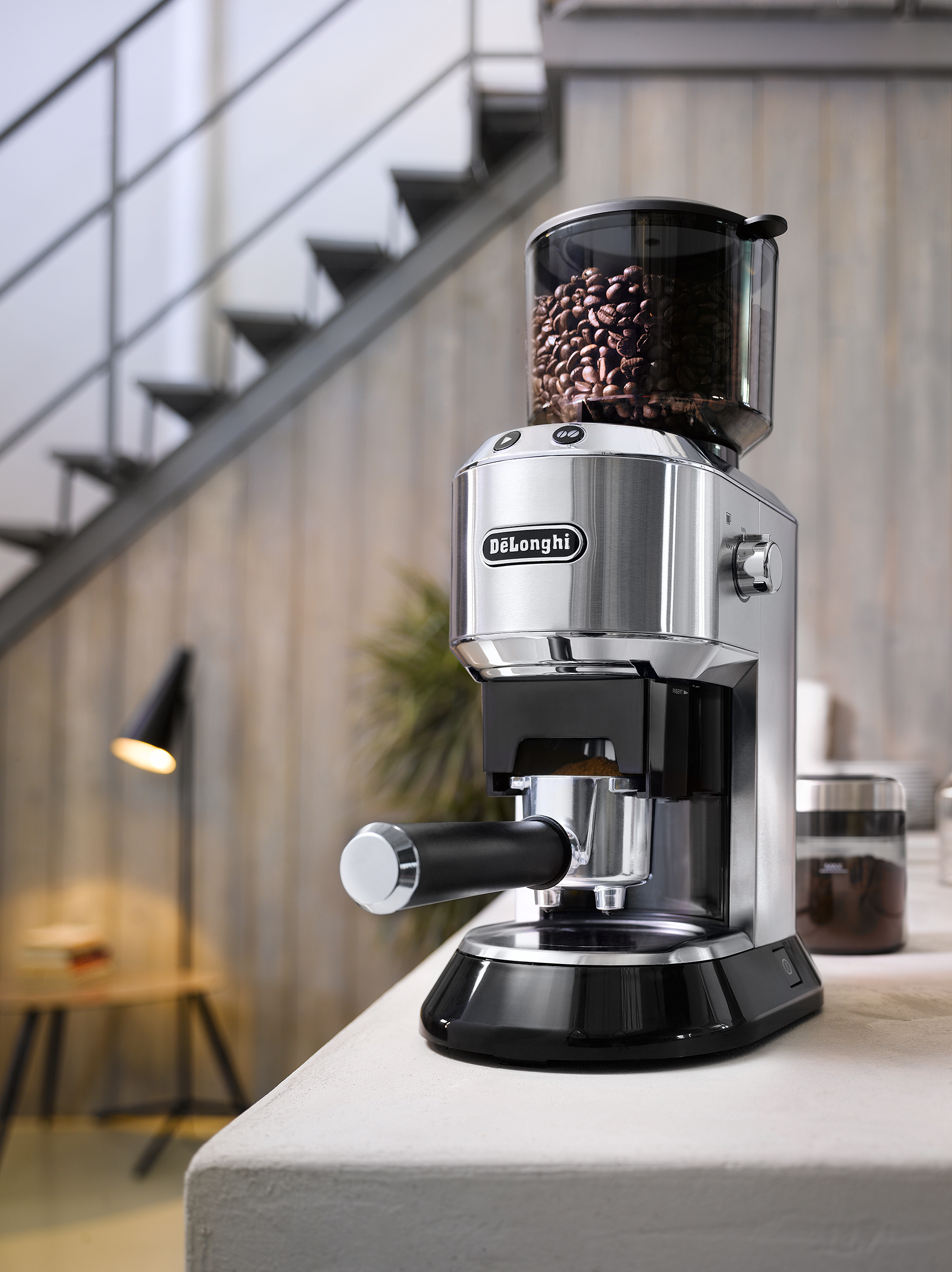 Eine silberne und schwarze Kaffeemühle mit Bohnenbehälter und einem eingesetzten Siebträger.
