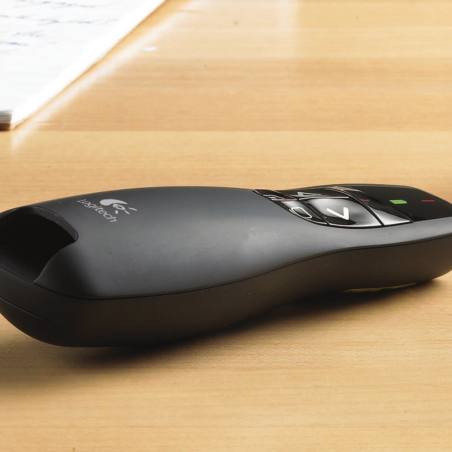 Eine schwarze Logitech Präsentationsfernbedienung auf einem Holztisch.