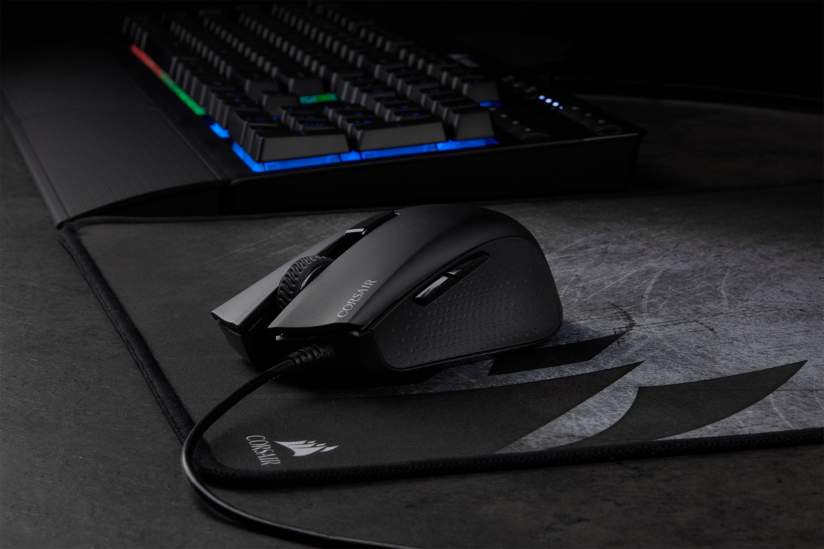 Souris noire avec fil sur tapis de souris noir. Clavier en arrière-plan.