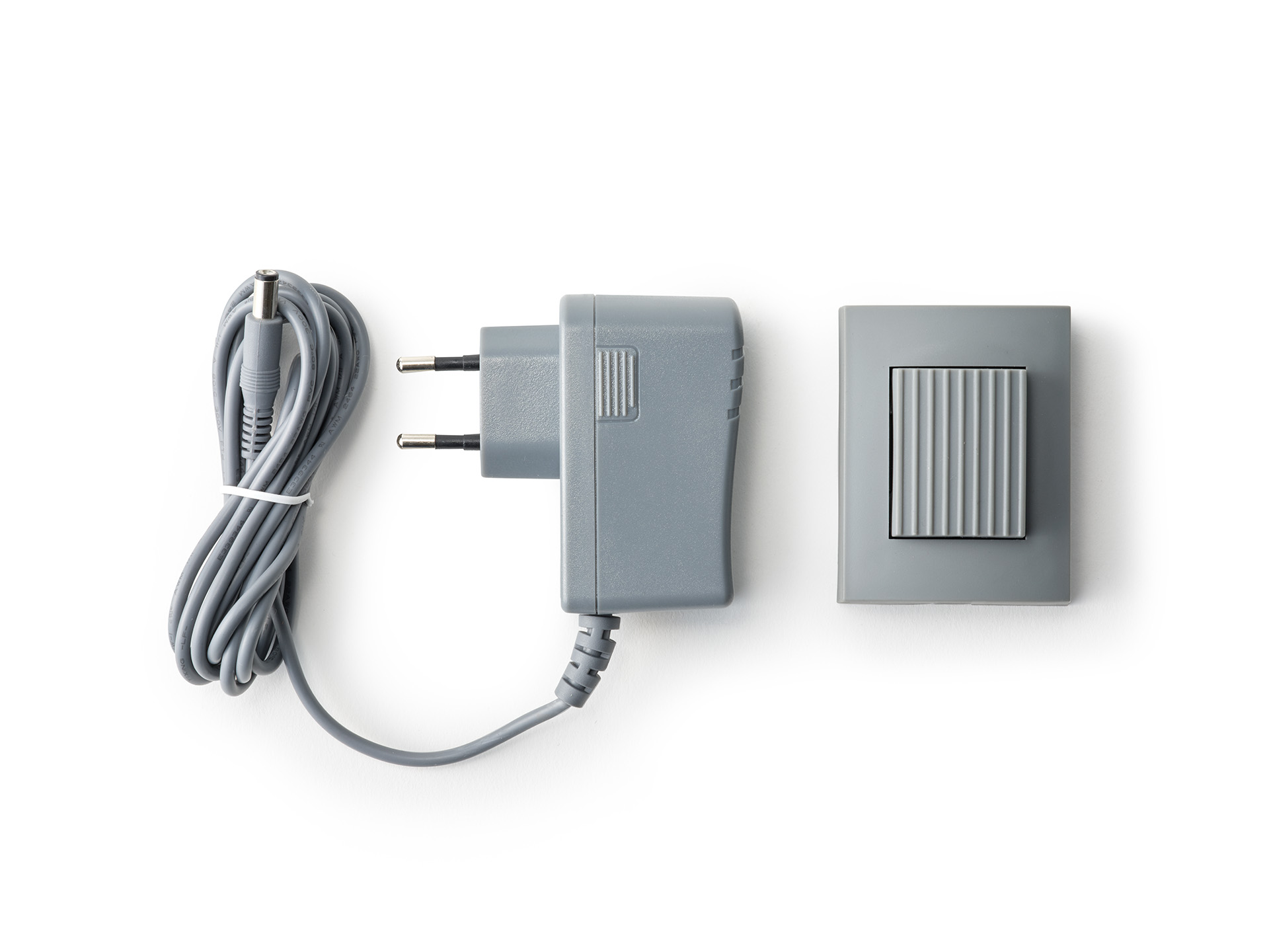 Graues Netzteil und Schalter mit gewickeltem Kabel auf weißem Hintergrund.