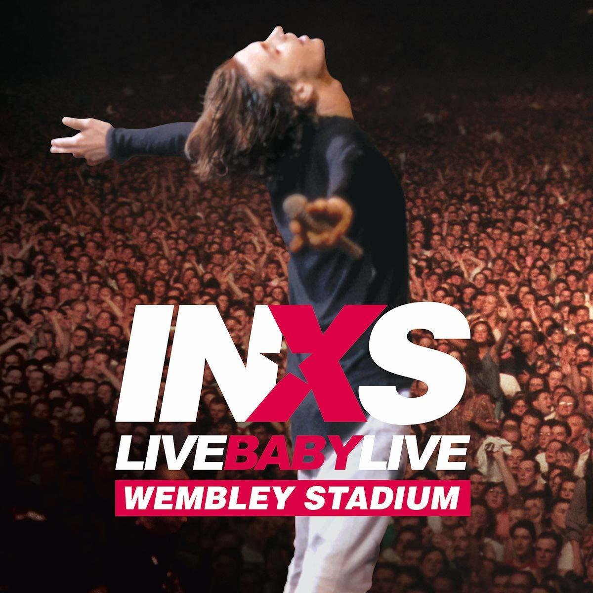 Pochette d'album : INXS Live Baby Live Wembley Stadium. Chanteur en pantalon blanc, bras levés devant la foule.