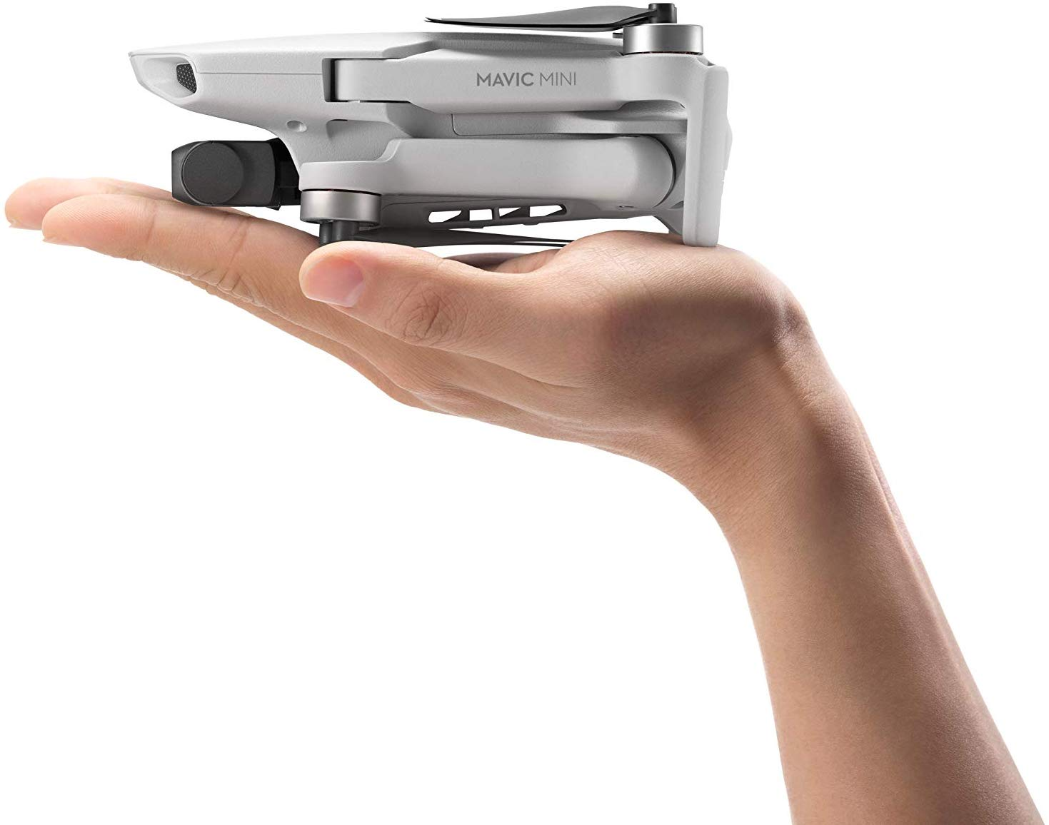 Dron blanco sostenido en una mano. Es un Mavic Mini, compacto y plegado. La mano está en primer plano.