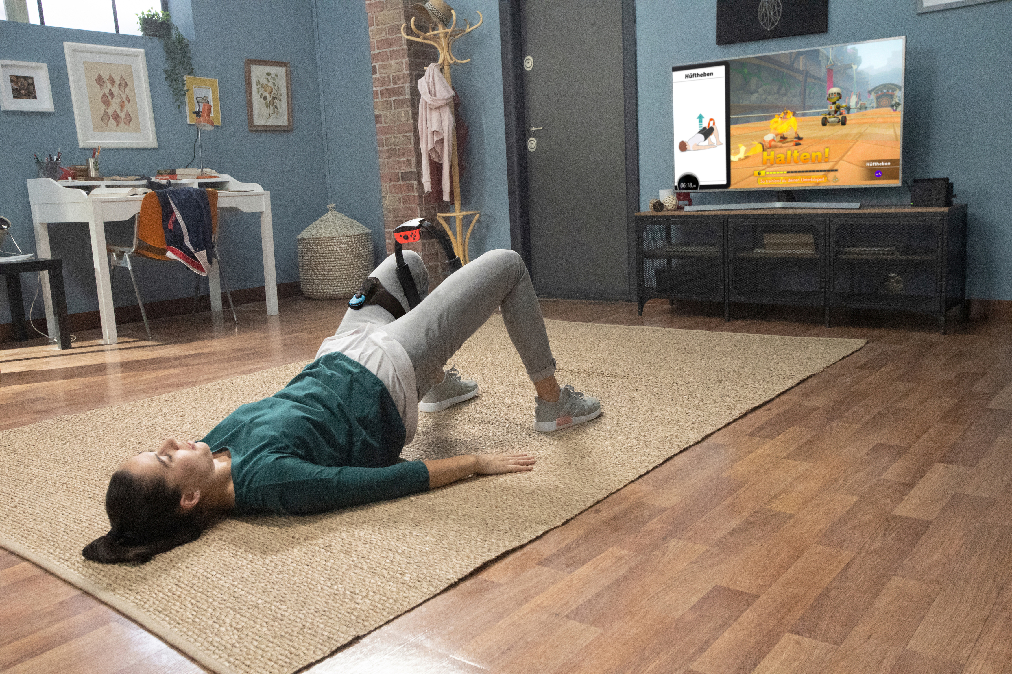 Frau trainiert drinnen mit sichtbarem Konsolenbildschirm, auf einer Yogamatte.