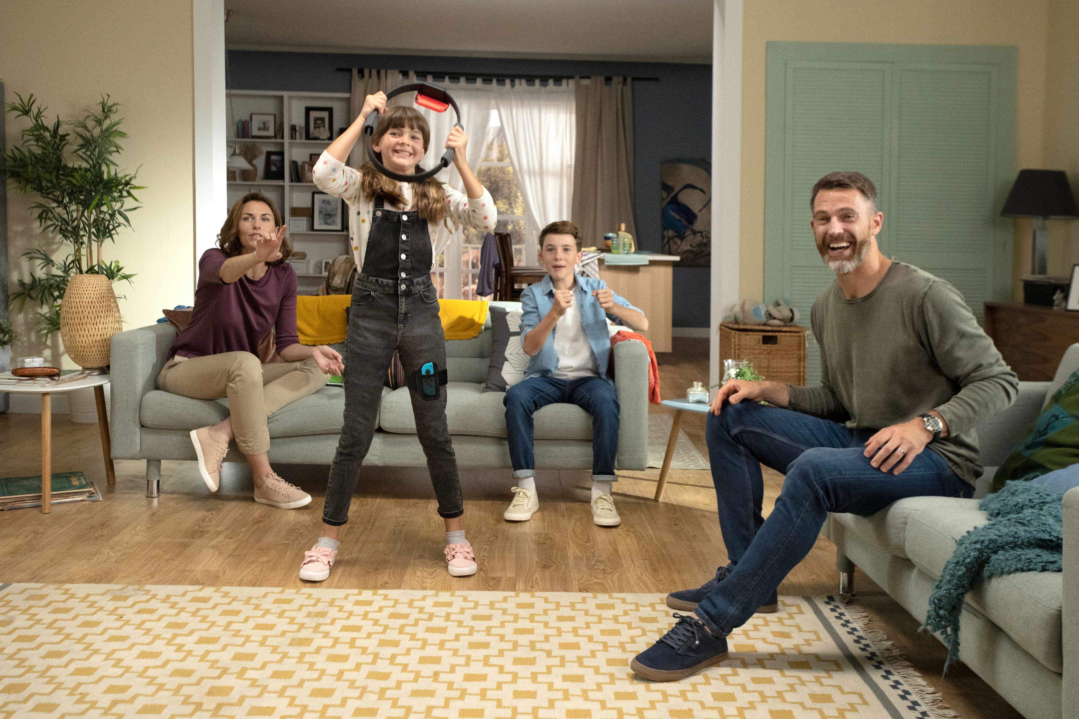 Familie spielt mit einem ringförmigen Gamecontroller. Wohnzimmerumgebung.