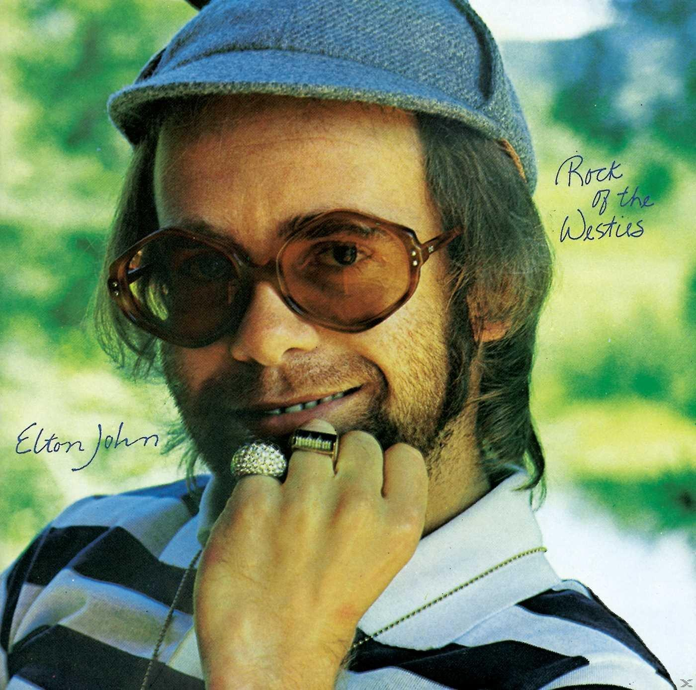 Elton John, szemüveggel, kalappal és gyűrűkkel, mosolyog. A háttérben lombozat látható, a szöveg pedig a "Rock of the Westies" és az "Elton John".