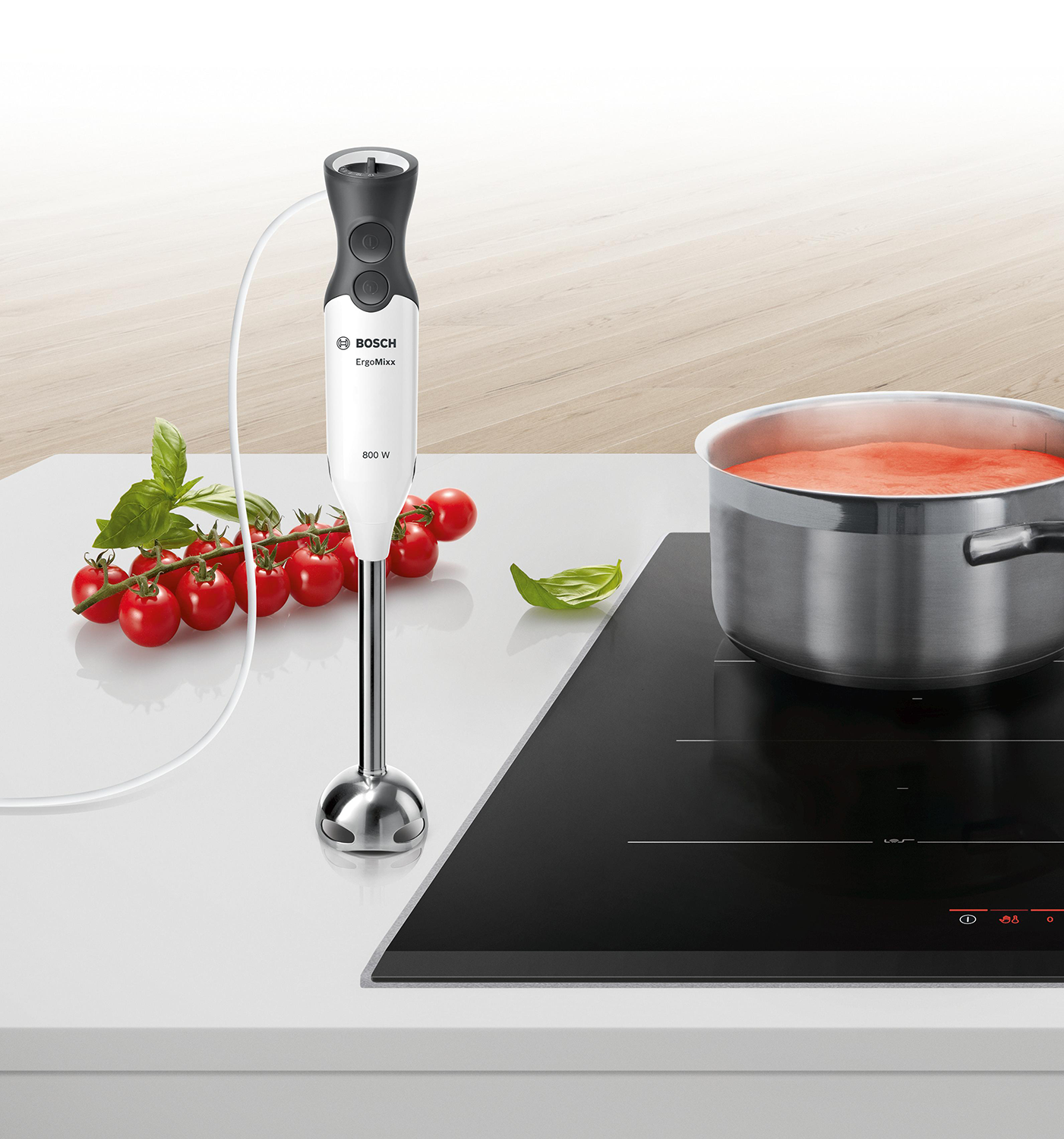 Immersion blender and ingredients on counter, next to a pot on a stove.