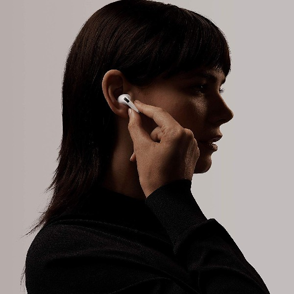 Una mujer con camisa negra se pone un auricular blanco en la oreja.