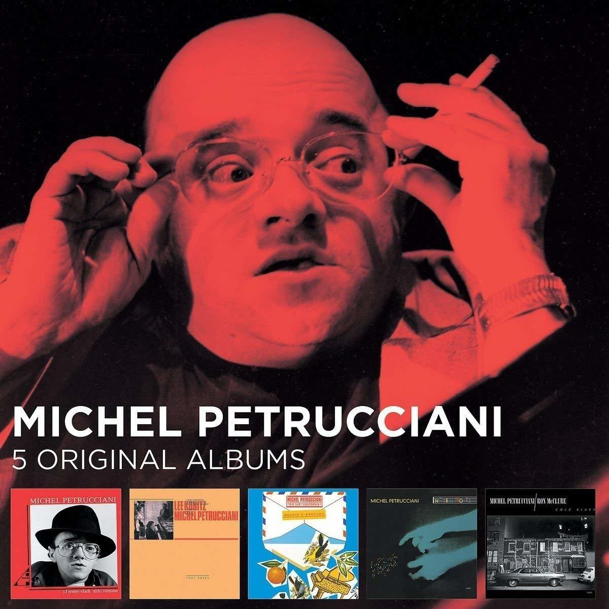 Ein Mann mit Brille und ein Poster mit mehreren Albumcovern.