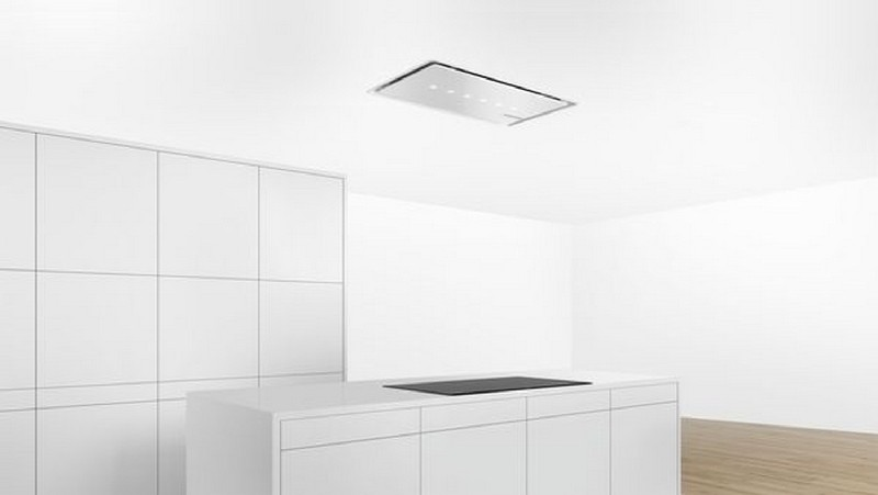 Cocina blanca moderna con isla blanca y campana extractora de techo integrada.