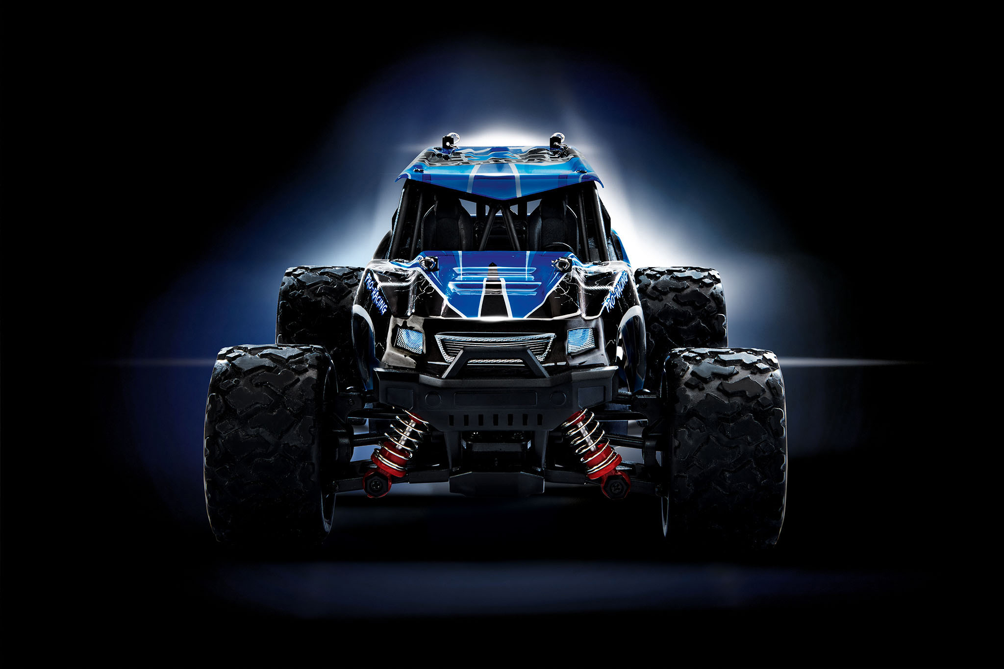 Ein blau-schwarzes RC-Car mit großen Reifen auf dunklem, verschwommenem Hintergrund.