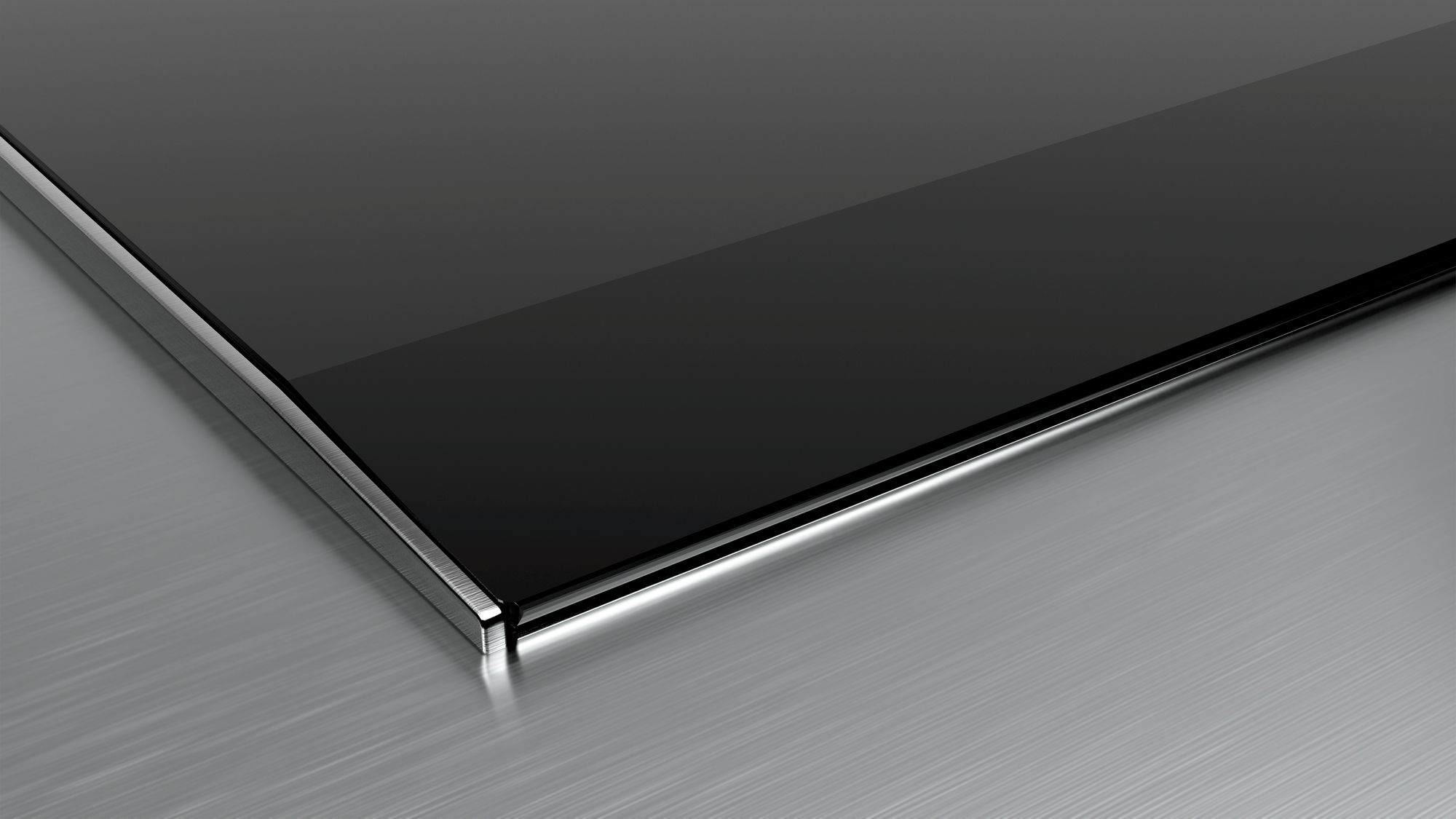 Gros plan sur une table de cuisson en verre noir avec un cadre en acier inoxydable.