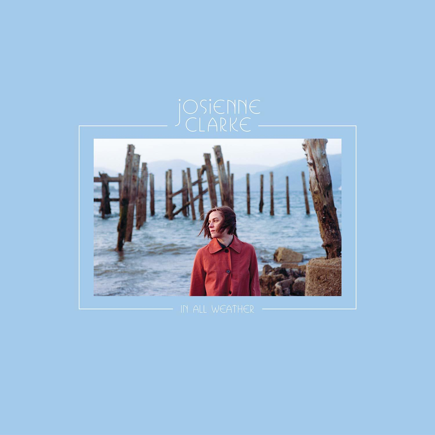 Albumcover mit Frau in rotem Mantel, mit Holzpfählen und Wasser im Hintergrund.