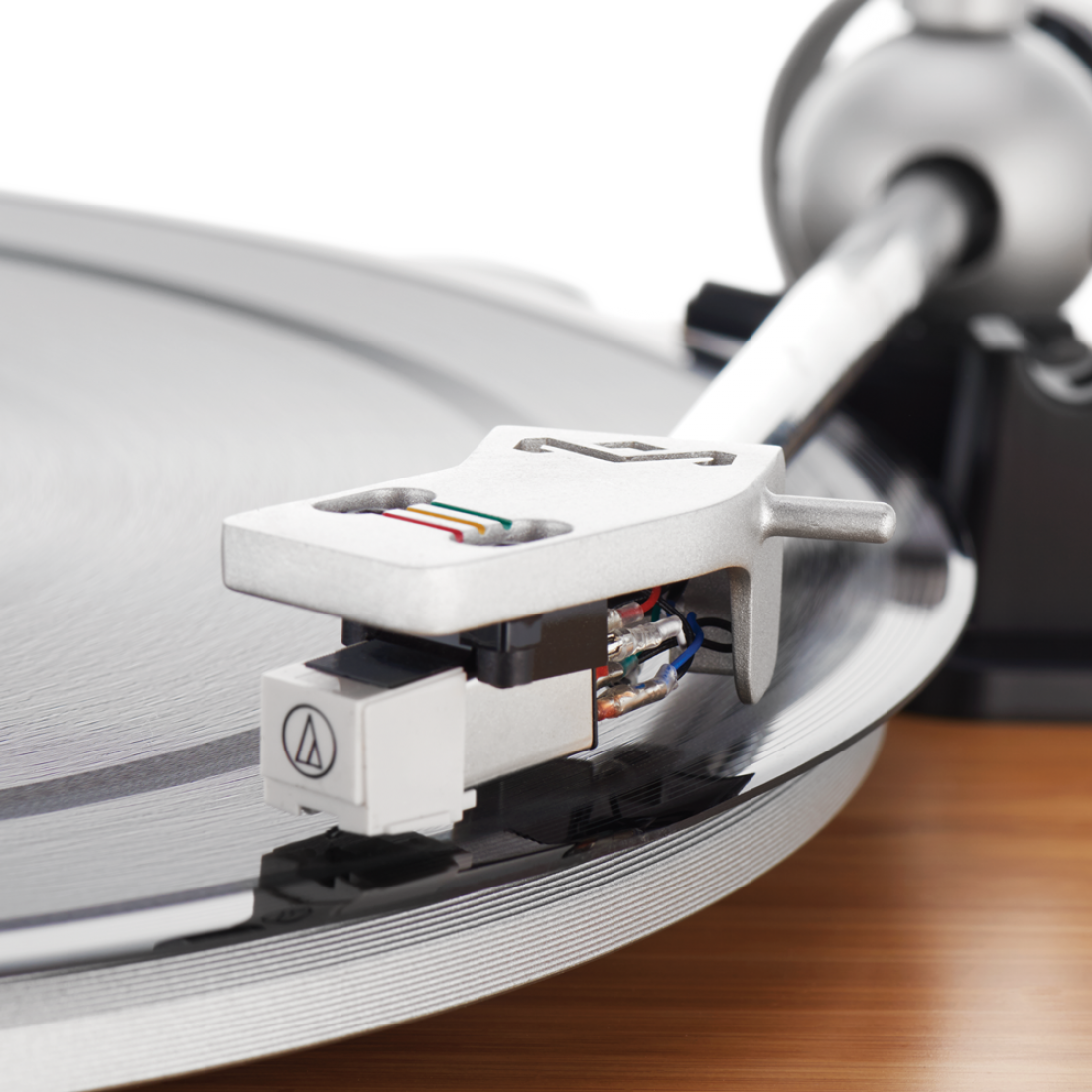 Aiguille de platine sur disque. Aiguille et bras argentés, socle en bois. Logo Audio Technica.