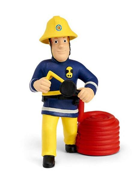 Ein Spielzeugfeuerwehrmann in gelbem Helm und Hose, marineblauem Hemd, hält einen Schlauch, neben einer roten Schlauchrolle.