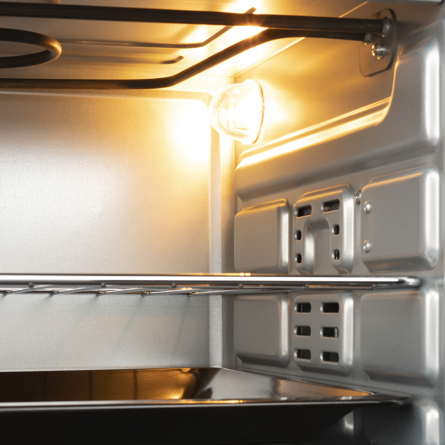 Inside of an oven with a light on, a metal rack, and a baking tray.