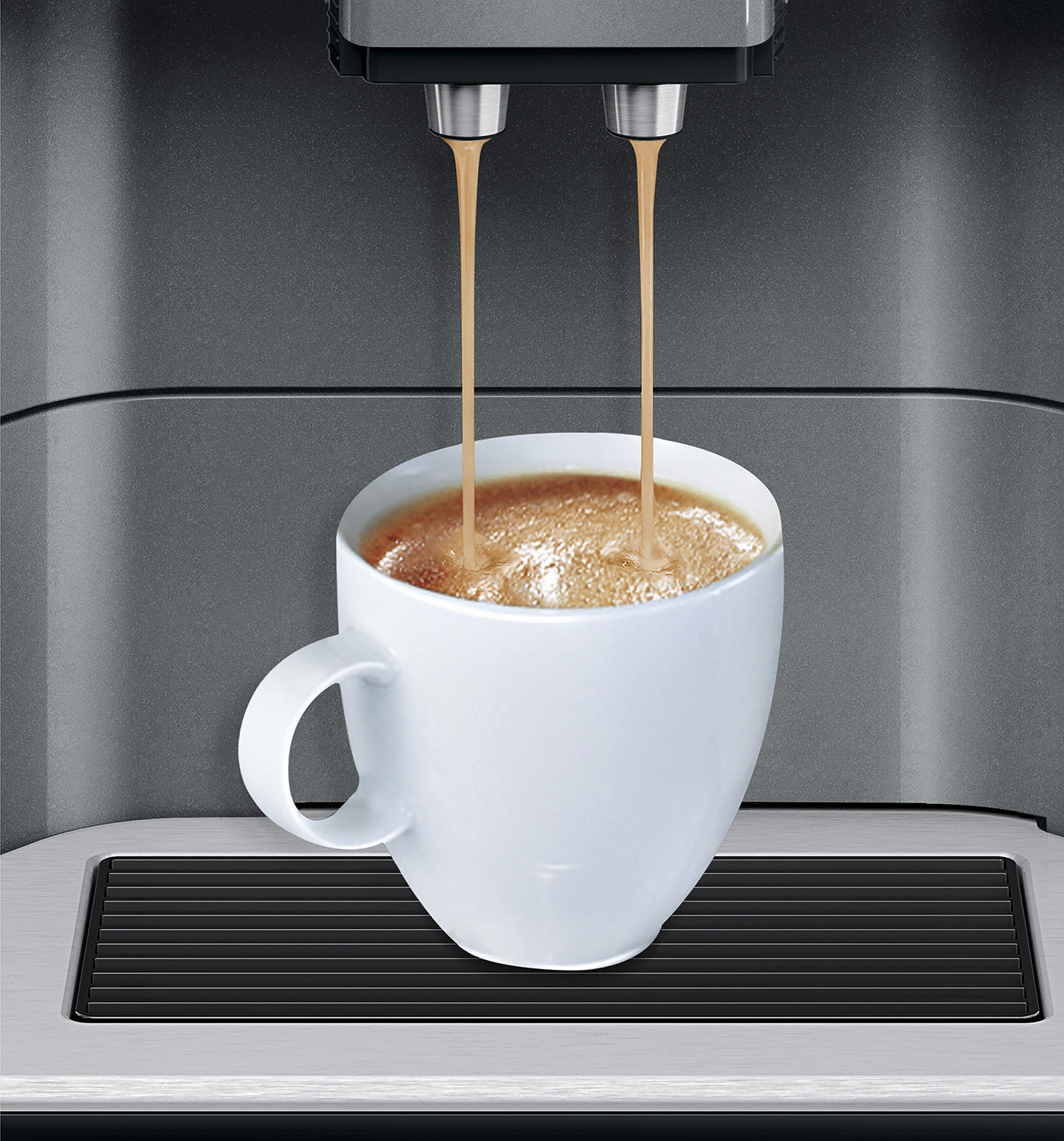 Koffie die uit een machine in een witte mok wordt gegoten. De machine is grijs.