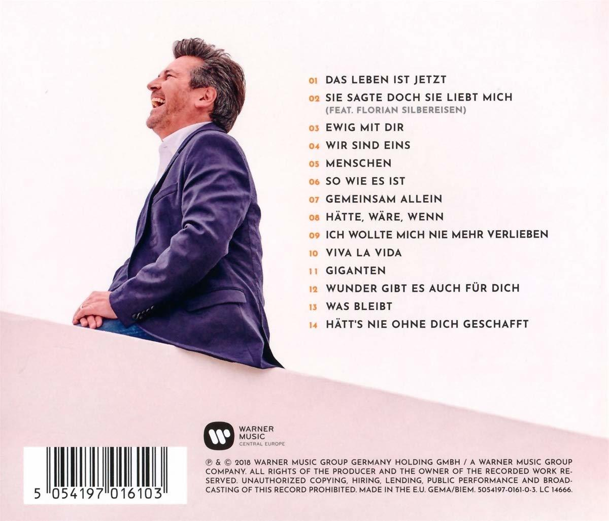 Mann lächelt mit einem CD-Albumcover im Hintergrund. Weißer Hintergrund, Text und Logos.