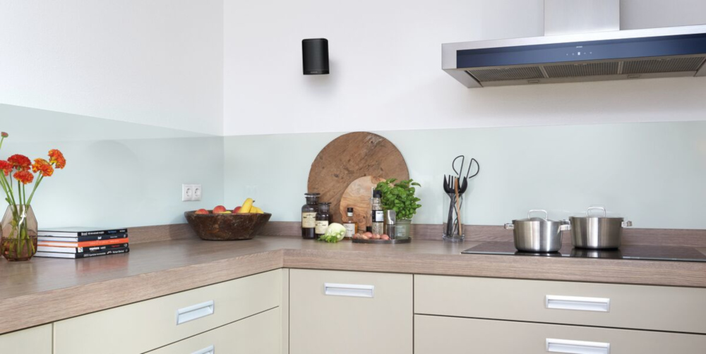 Kitchen corner with countertop and cabinets. A black speaker is mounted on the wall.