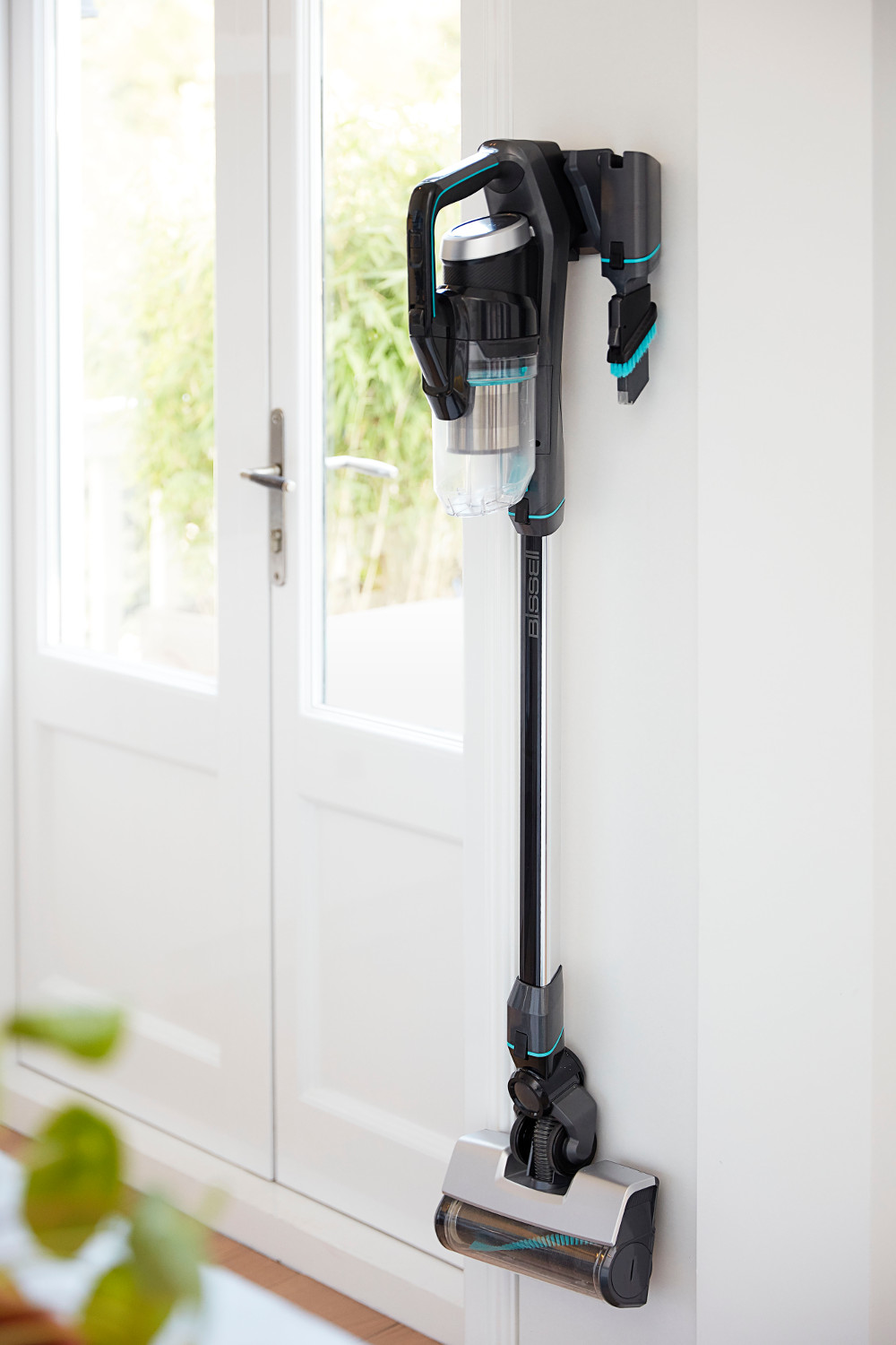 Aspirateur noir et argenté fixé sur un mur blanc, près d'une porte.