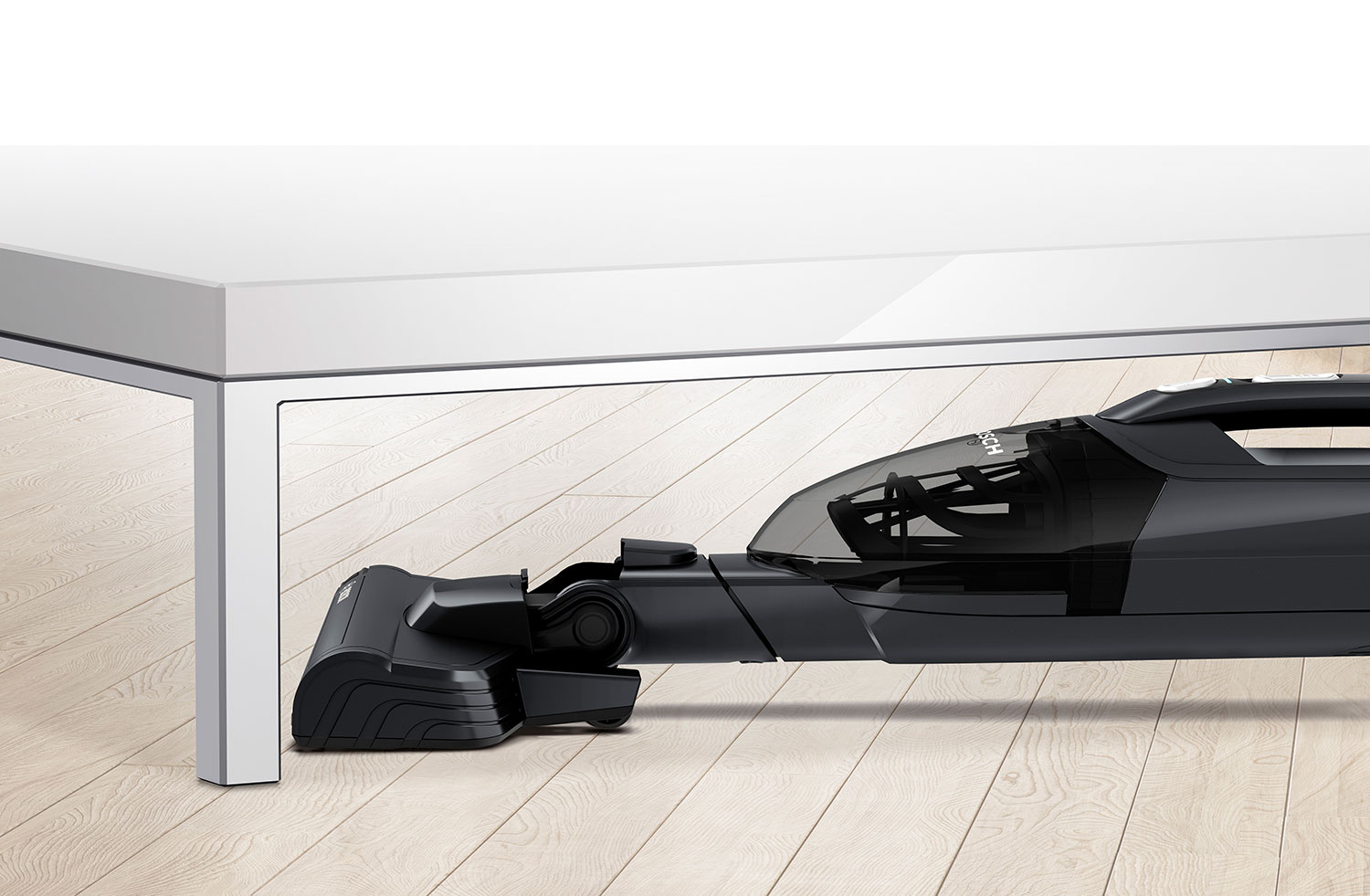 Black vacuum cleaner head is shown under a white table, on wooden flooring.