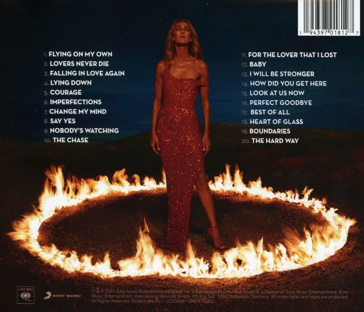 Celine Dion steht in einem roten Kleid auf einer Bühne mit Feuer um sie herum.