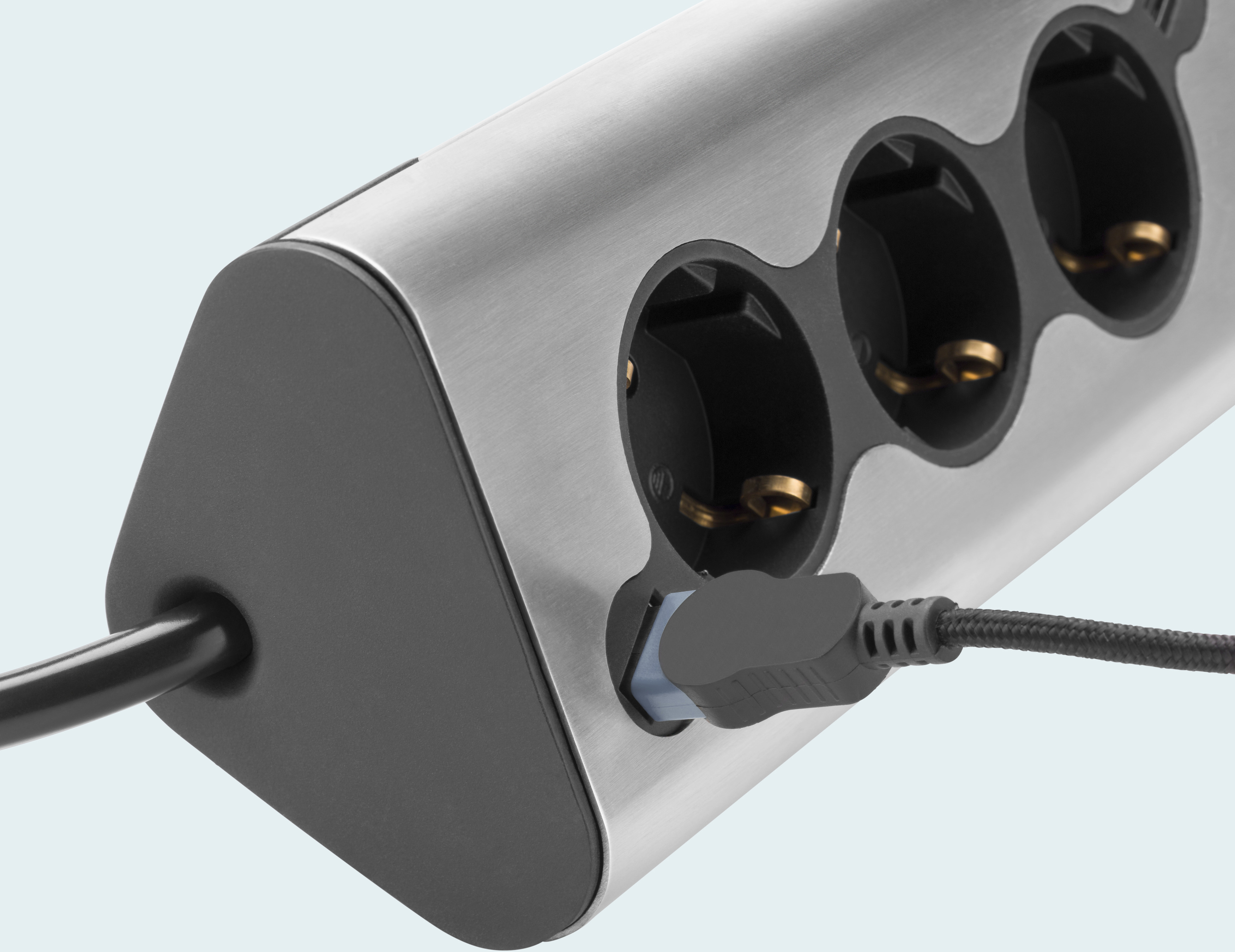 Eine silberne und schwarze Steckdosenleiste mit drei Steckdosen und einem angeschlossenen USB-Stecker.