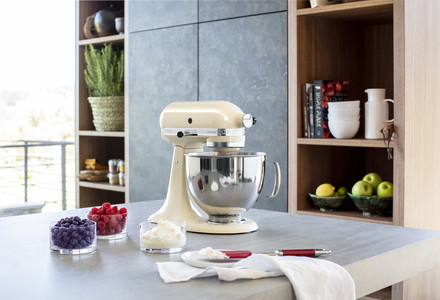 Küchenszene mit Standmixer, Früchten, Schalen und Zutaten auf einer Arbeitsplatte.