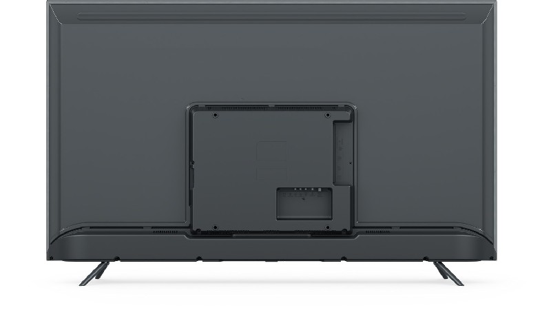 Parte trasera de un televisor gris. Tiene un panel rectangular con puertos y un soporte.
