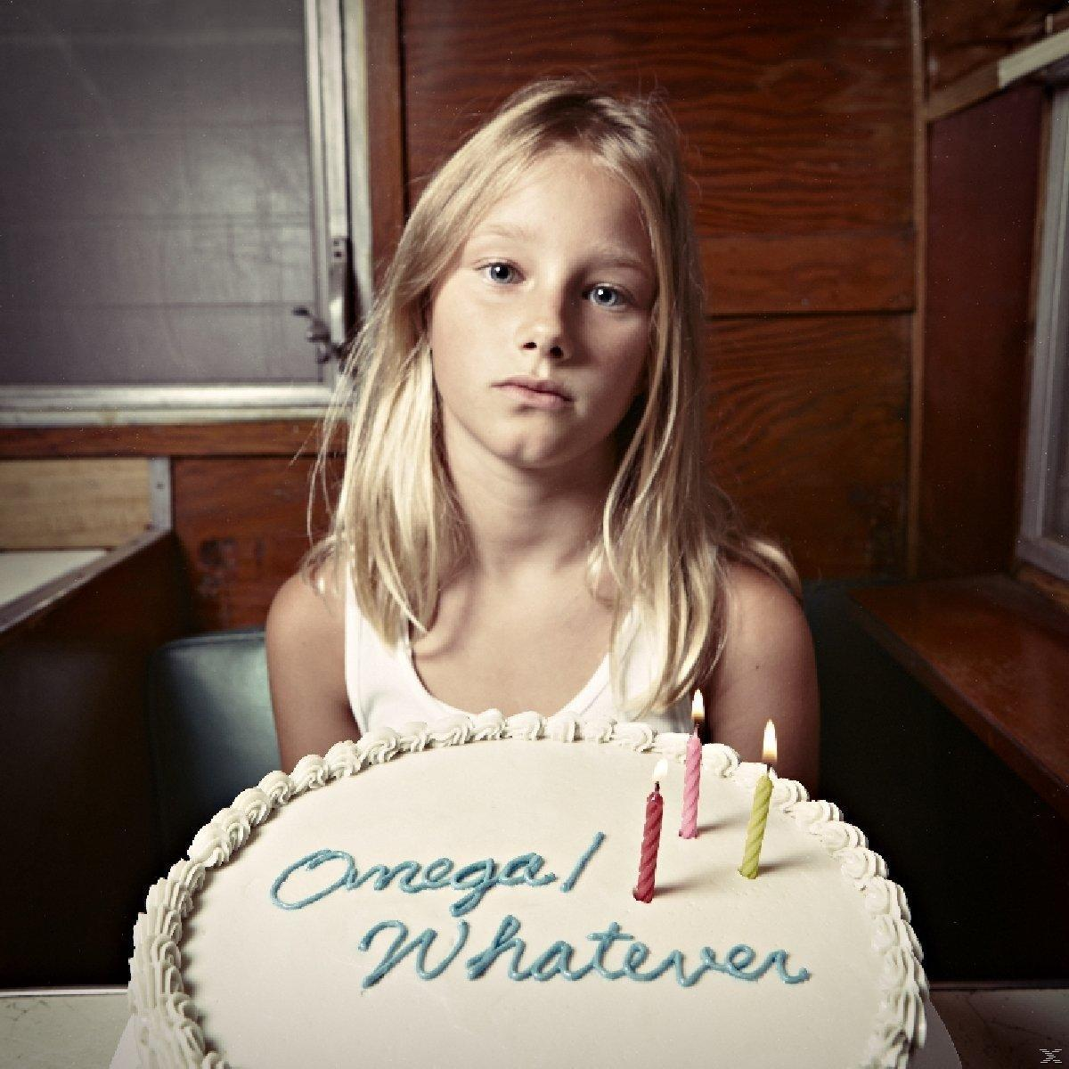 Blondes Mädchen schaut in die Kamera. Ein Kuchen mit Kerzen und den Worten 'Omega/Whatever' ist vor ihr.