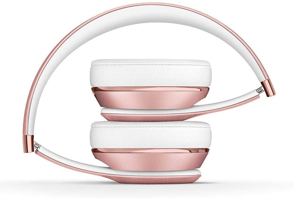 Auriculares plegados en oro rosa y blanco, sobre un fondo blanco. El oro rosa es brillante.