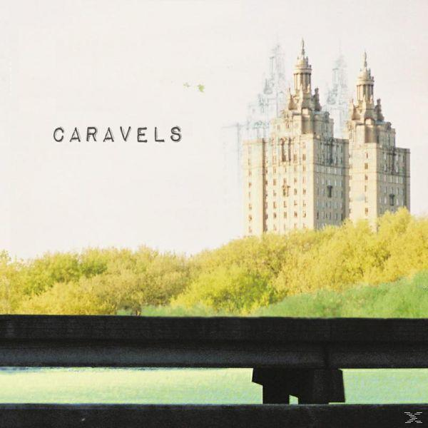 Albumcover: 'Caravels' mit einem verschwommenen Bild eines Gebäudes hinter Bäumen und einem schwarzen Zaun.