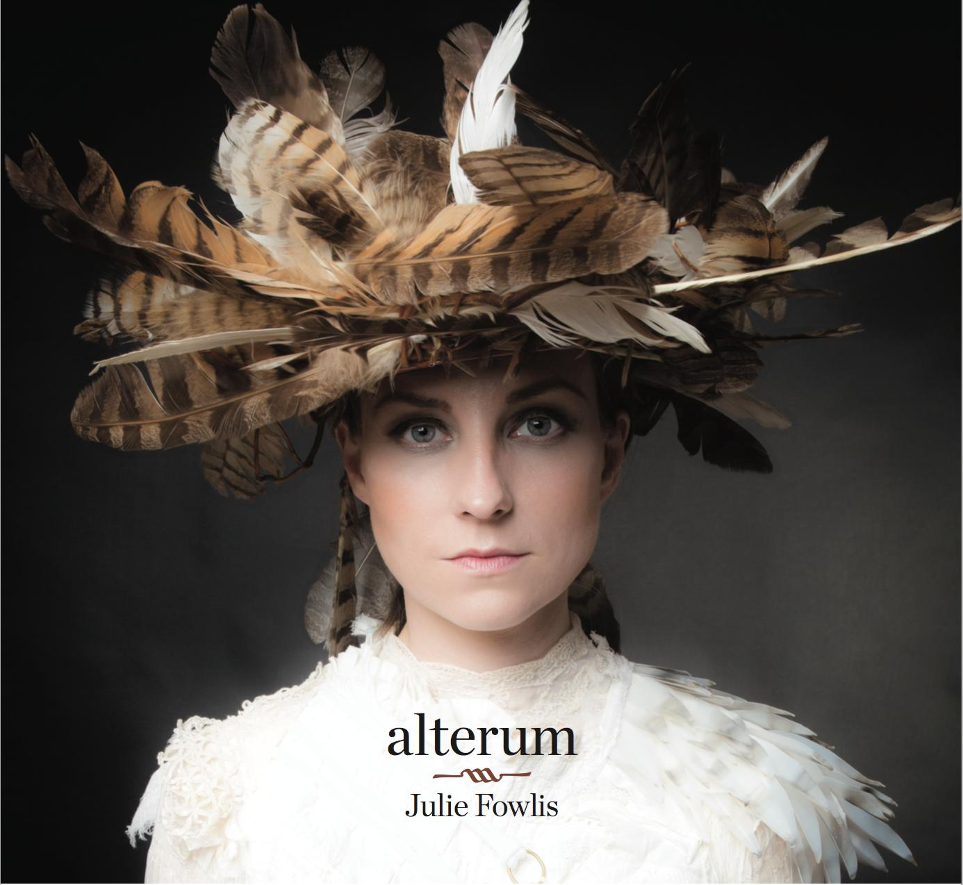 Eine Frau mit einem Federhut auf dem Kopf. Sie trägt ein weißes Kleid. Der Albumtitel lautet 'alterum'.